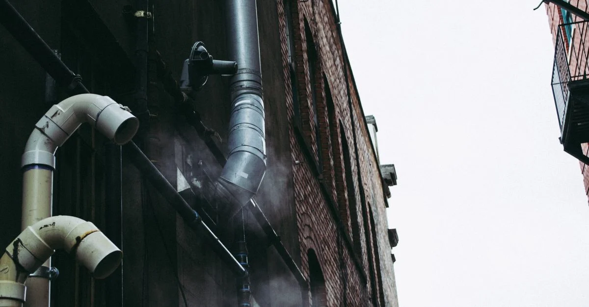 Un callejón urbano con una atmósfera mostrando tuberías metálicas expuestas y humo, mostrando la arquitectura industrial.