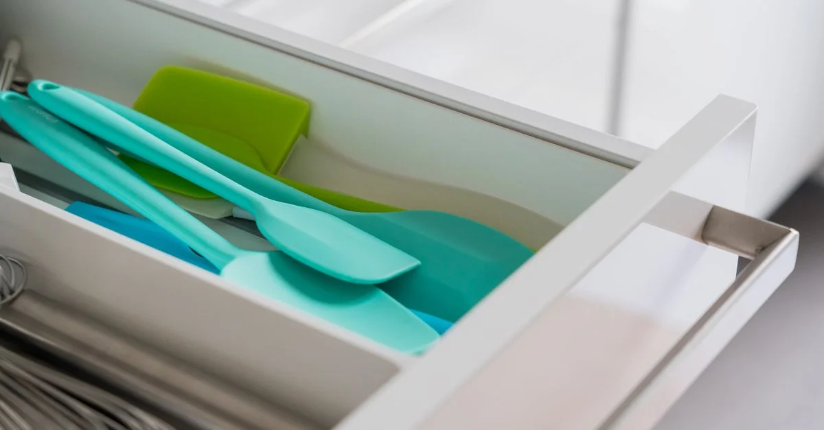 Un cajón de cocina ordenado con espátulas de silicona y un batidor.