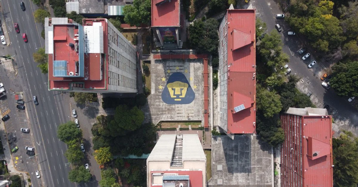Toma aérea de edificios con el emblema de Pumas UNAM en Ciudad de México, vibrante entorno urbano.