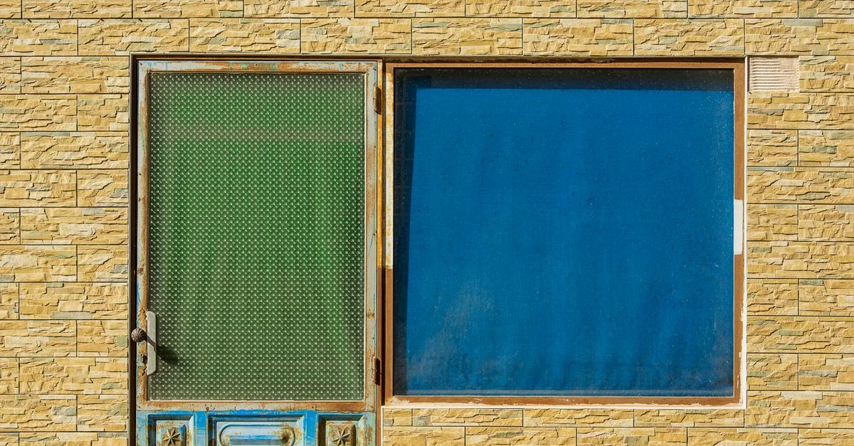 Una vibrante fachada de edificio de piedra con una puerta verde y una ventana azul.