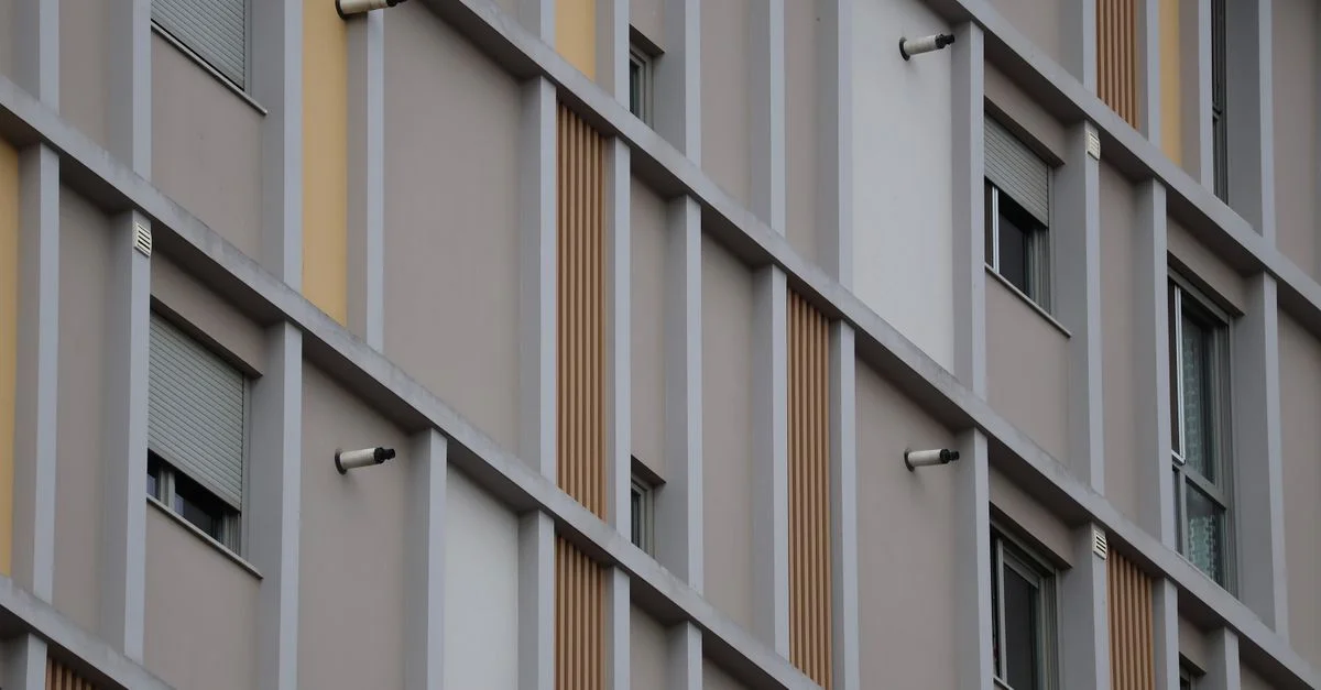 Fachada contemporánea de edificio que muestra un patrón de ventanas y texturas en un entorno urbano.