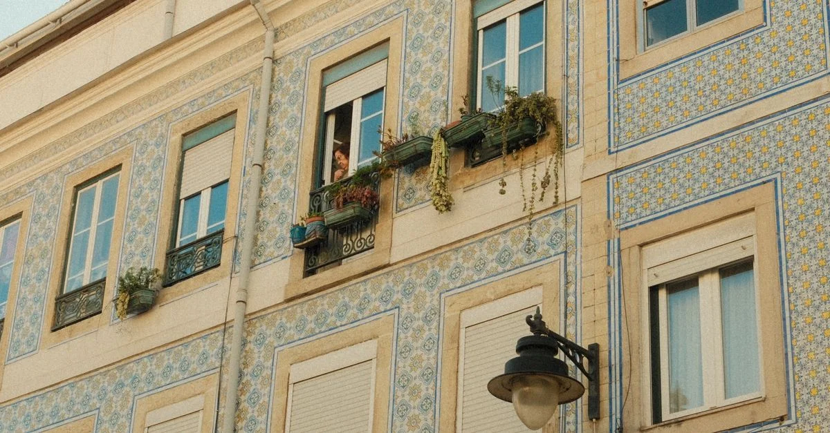Fachada histórica de Lisboa con azulejos y una persona mirando hacia afuera. Captura el encanto arquitectónico portugués.
