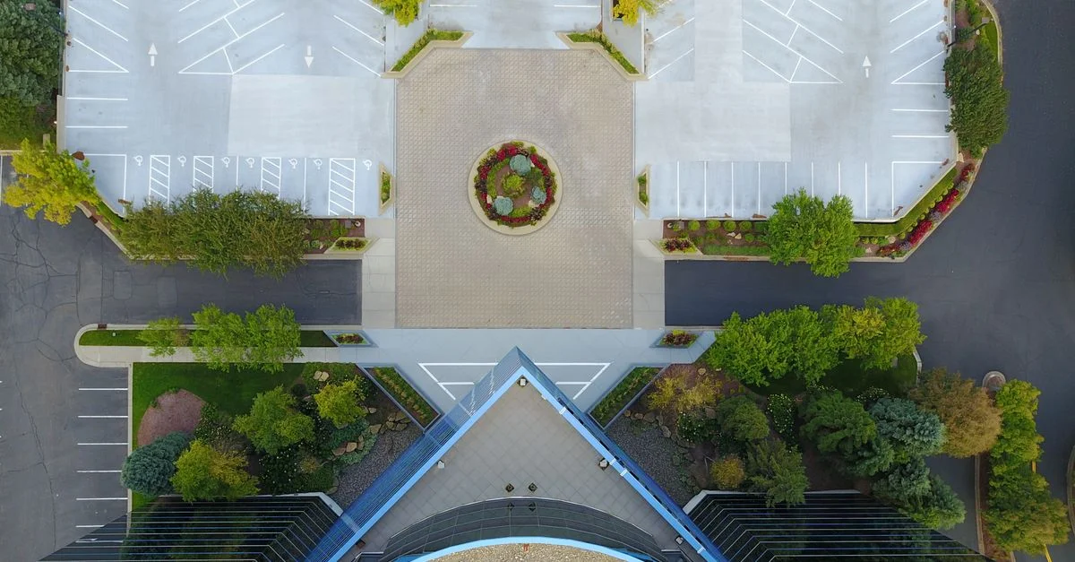 Vista de arriba hacia abajo de un edificio moderno y un estacionamiento vacío, que muestra simetría y diseño urbano.