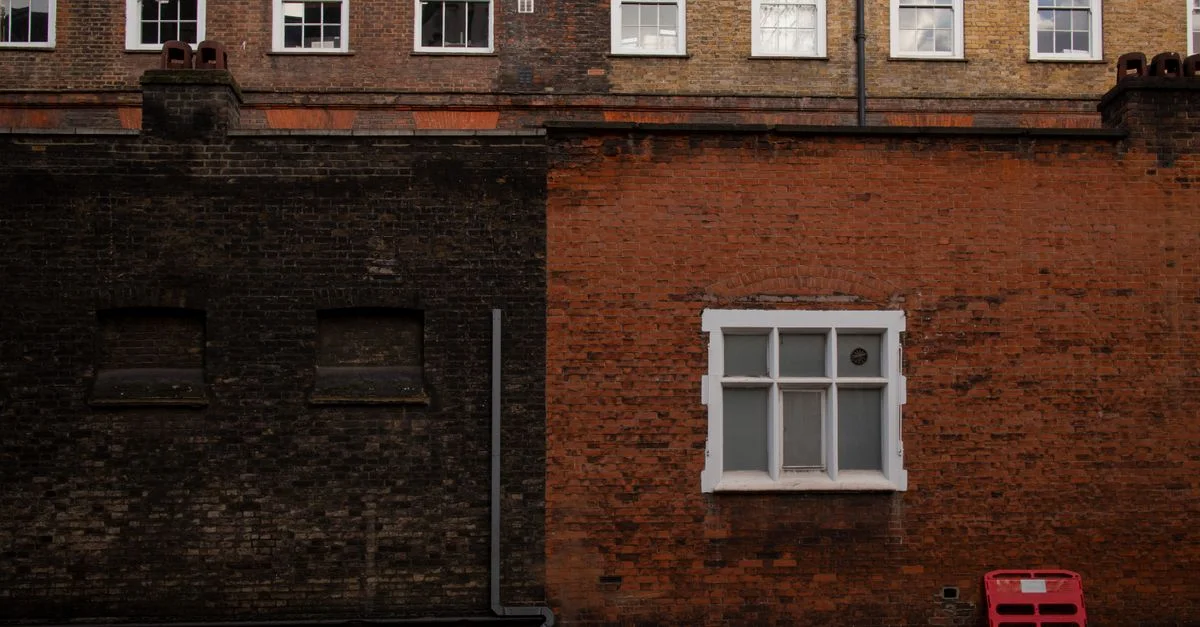 Una vista detallada de una pared de ladrillos clásica en Londres con ventanas y detalles arquitectónicos.