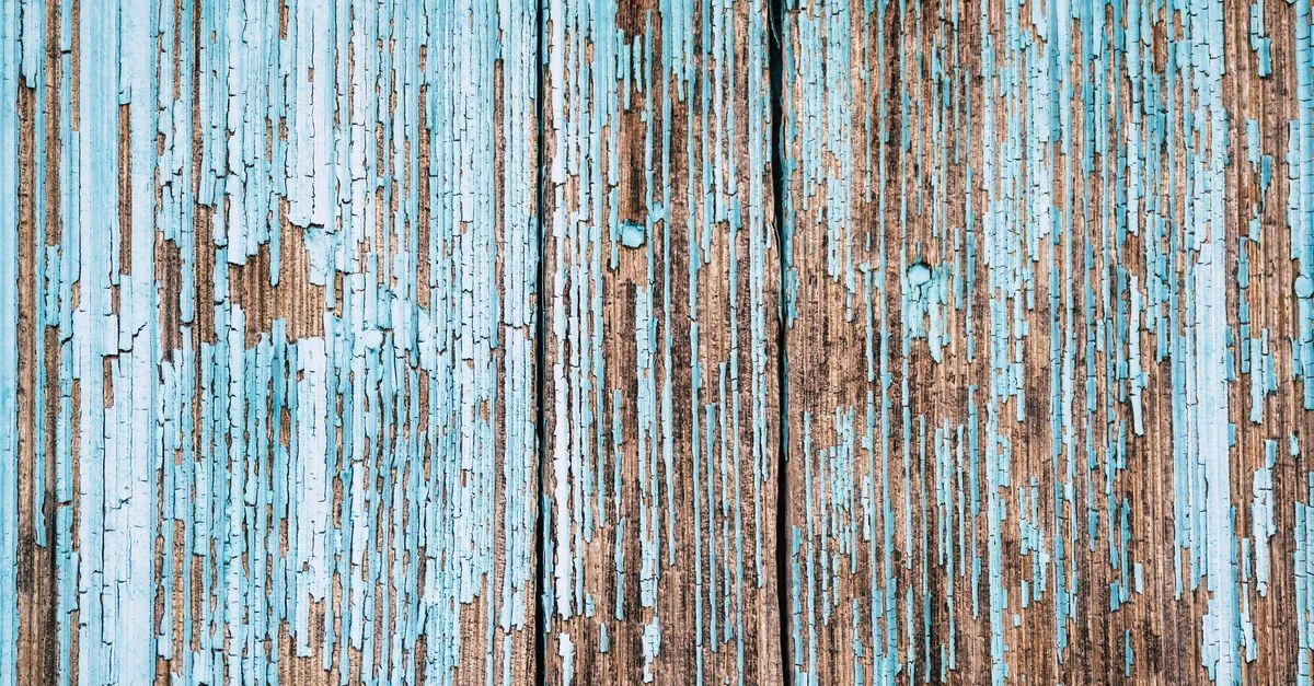 Primer plano de una superficie de madera envejecida con pintura azul descascarada, mostrando textura y envejecimiento.