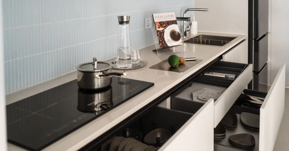 Diseño de cocina moderno y elegante con cajones abiertos y estufa de inducción que resalta el estilo contemporáneo.